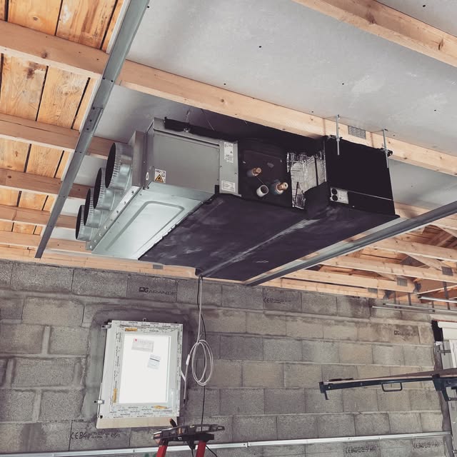 Pompe à chaleur gainable fixée sous plafond dans un garage